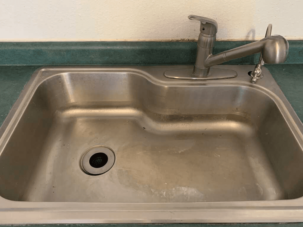 Dirty stainless steel kitchen sink before professional house cleaning