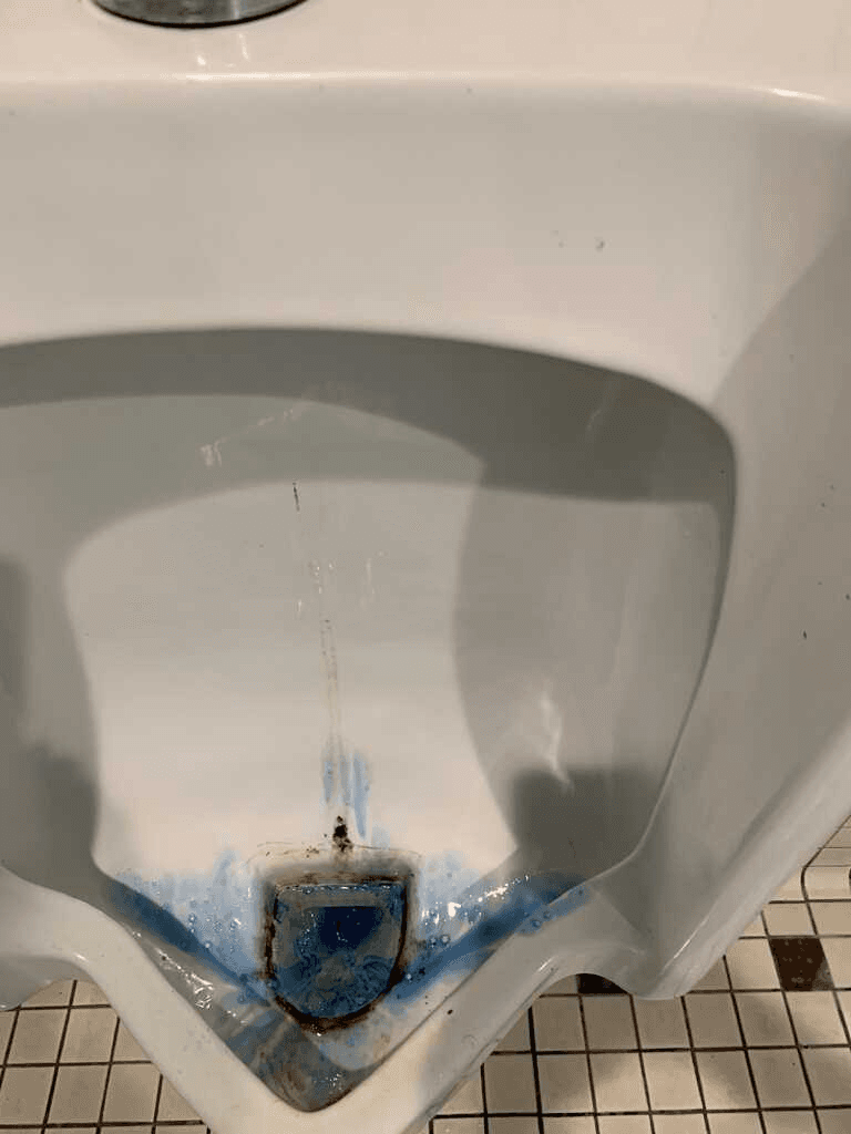 Stained commercial urinal before cleaning