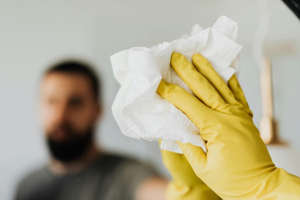 Close-up of professional mirror cleaning with yellow gloves and streak-free finish